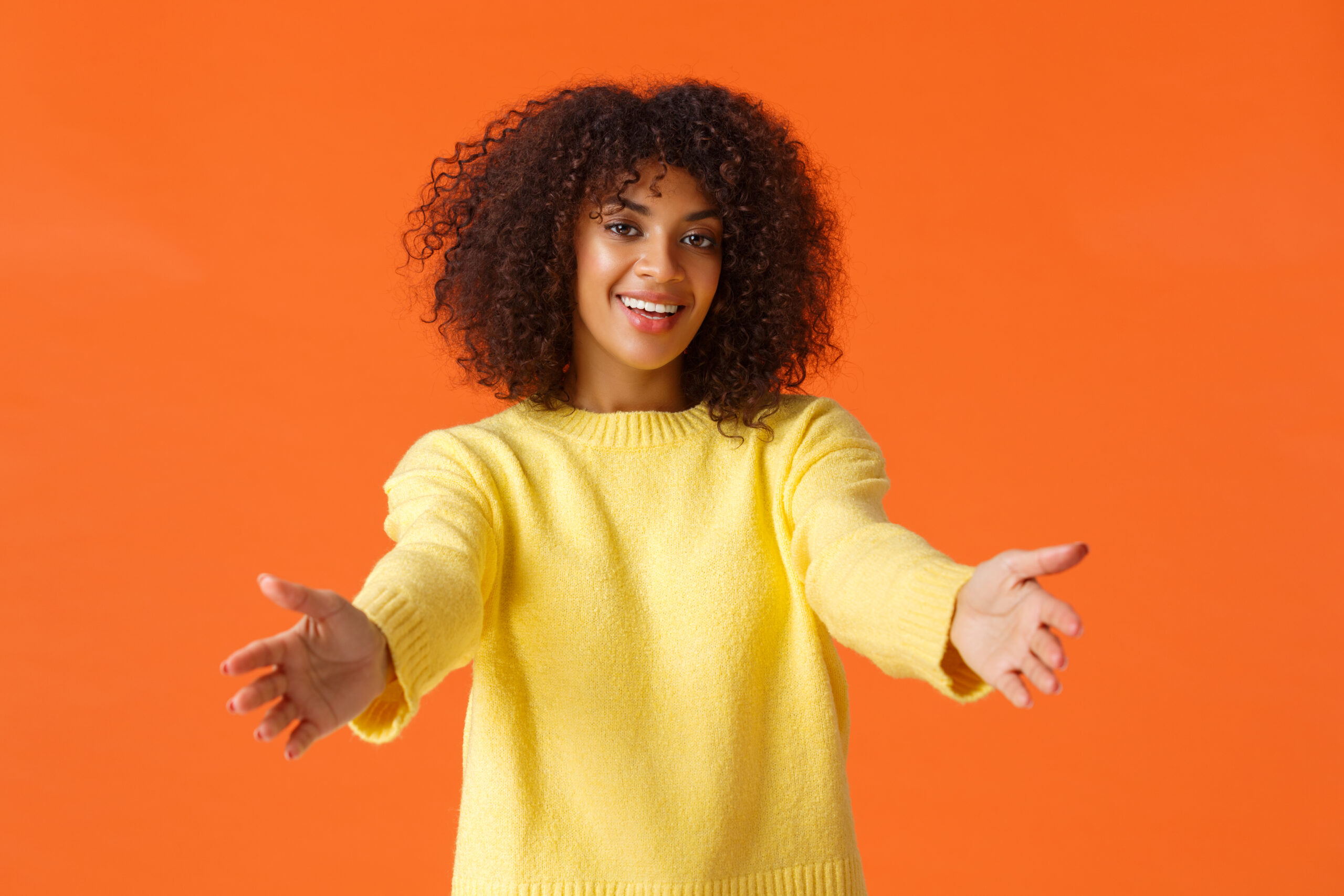 Come here, let me hug you. Cute friendly, attractive african american woman with curly hair, stretching hands forward, ready for cuddles, embracing friend and smiling happily, congratulating Come here, let me hug you. Cute friendly, attractive african american woman with curly hair, stretching hands forward, ready for cuddles, embracing friend and smiling happily, congratulating.